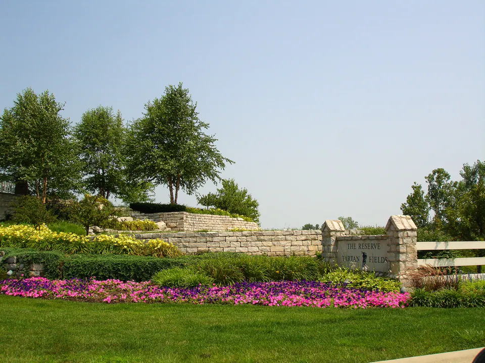 Layered evergreen, ornamental grass, shrub, and seasonal color planting around the Tartan Fields entry